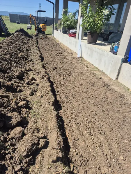 A hosszú árok a betonkerítés mentén.